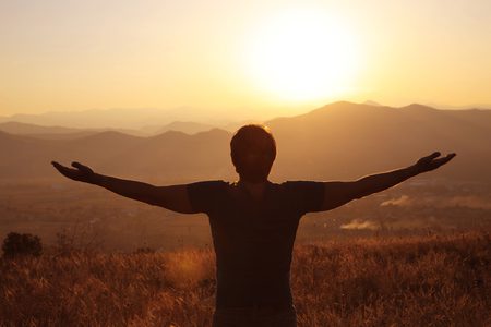 Persona disfrutando del atardecer con los brazos abiertos