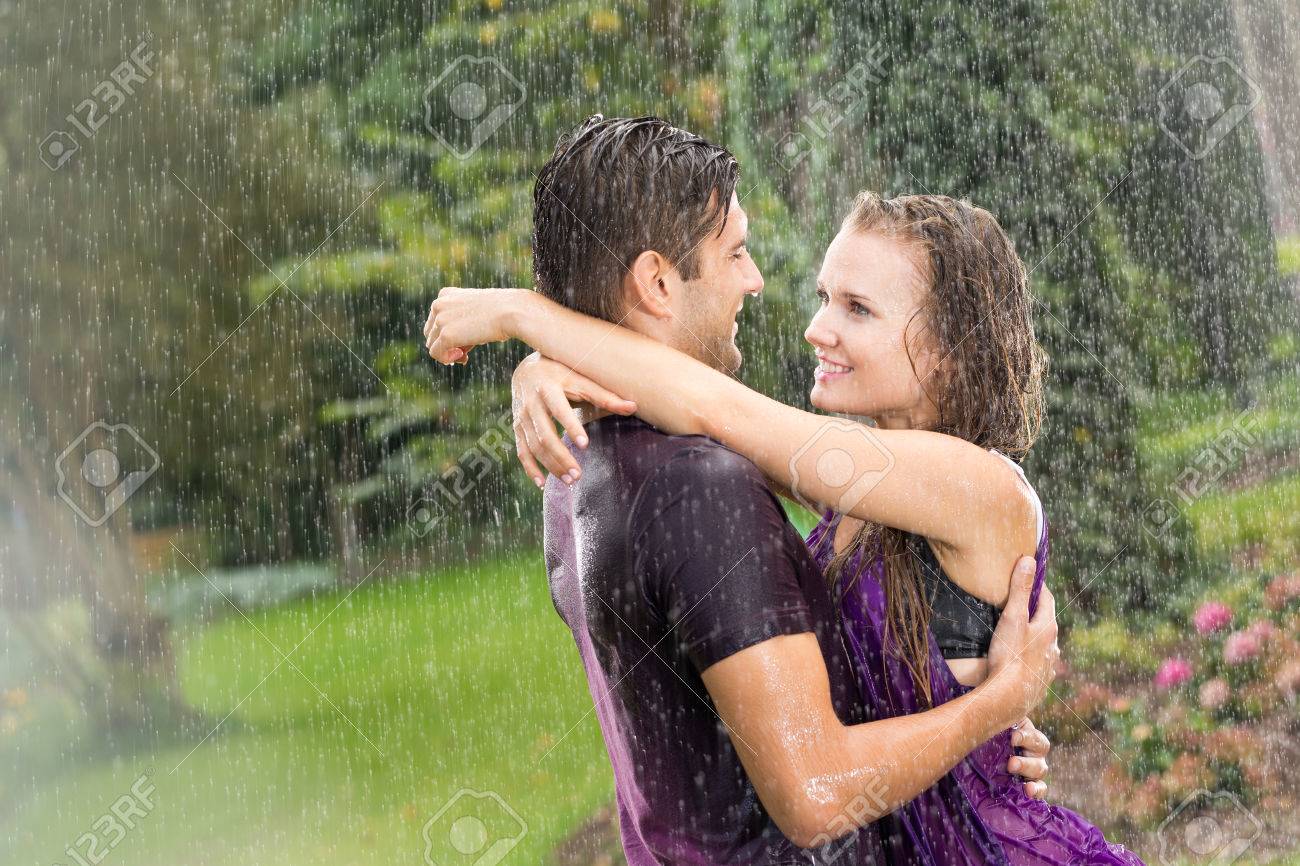 Una pareja bajo la lluvia, abrazados y sonriendo