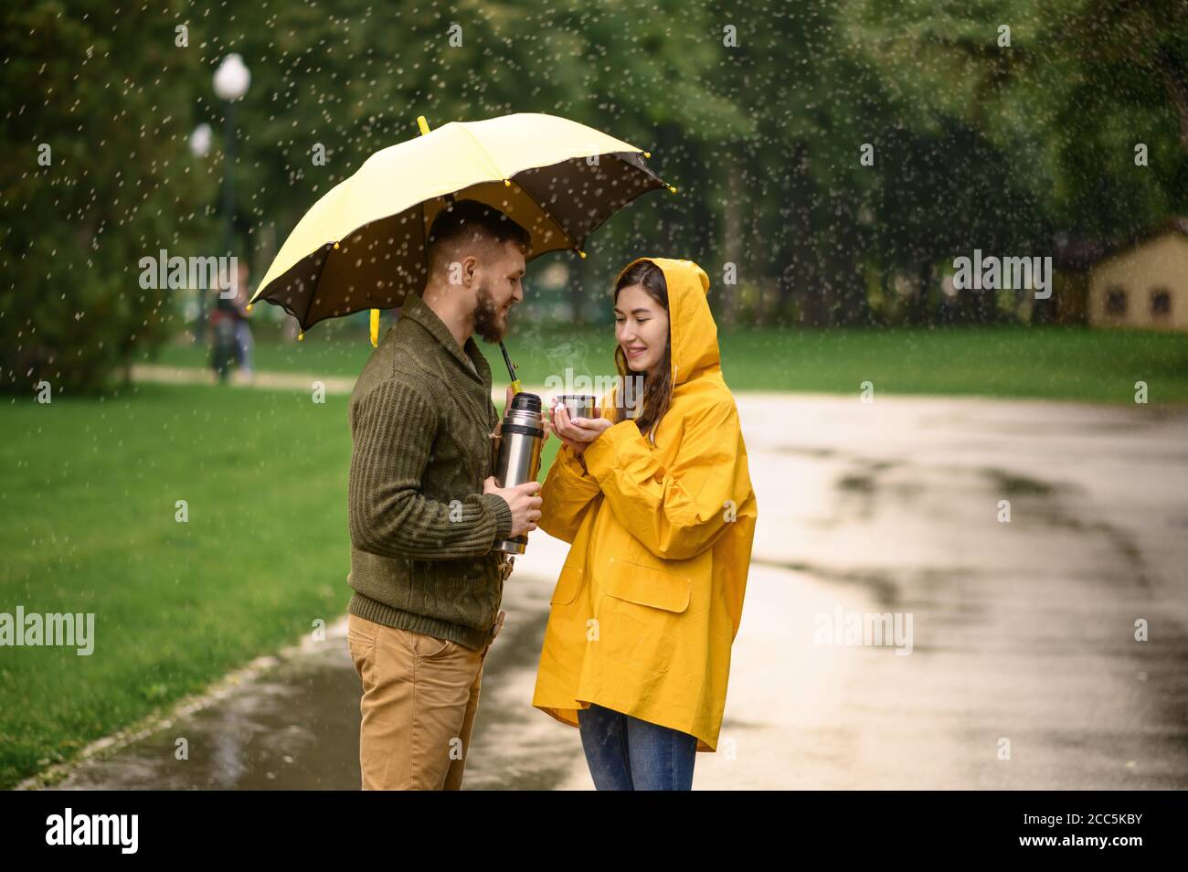 pareja de amor con te caliente en el parque dia lluvioso en verano 2cc5kby