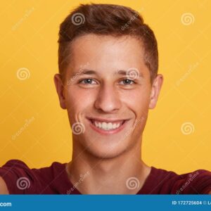 retrato de primer plano un joven carismatico y magnetico chico mirando directamente la camara sonriendo sinceramente teniendo 172725604